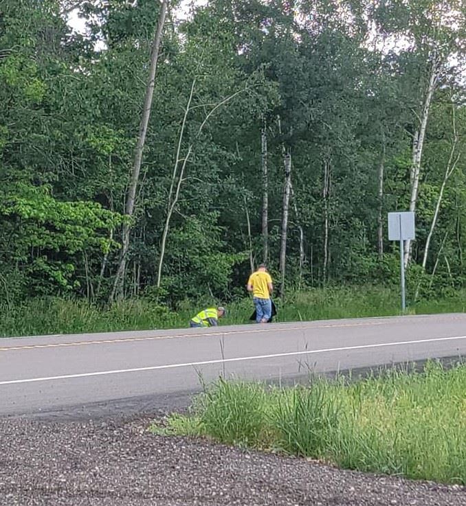 two people picking up trash in ditch 